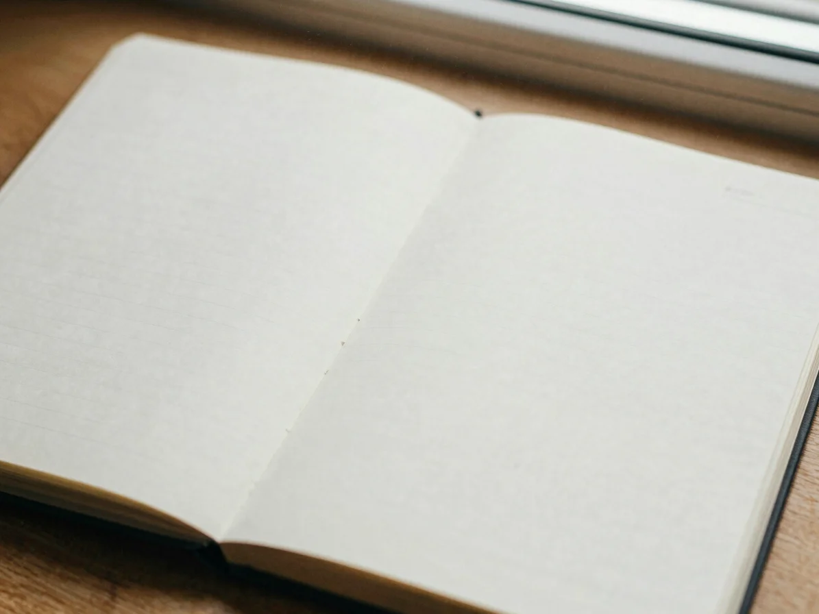 Editorial close-up of an open paper notebook on a wooden table, s